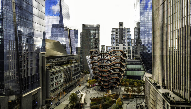Aerial view of The Vessel at Hudson Yards a copper colored honeycomb structure surrounded by modern glass skyscrapers and urban plazas in New York New York United States.