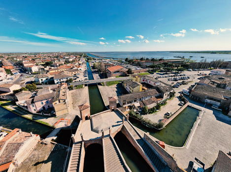 Aerial view of the historic Trepponti bridge and scenic canals surrounded by traditional brick houses in Comacchio Emilia Romagna Italy. Aerial view of the historic Trepponti bridge and scenic canals surrounded by traditional brick houses in Comacchio Emilia Romagna Italy.