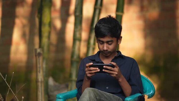 View of a young man using a smartphone outdoors Bangladesh. View of a young man using a smartphone outdoors Bangladesh.