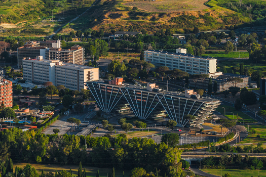 Aerial view of the modern architectural building with a distinctive triangular facade surrounded by lush trees and urban infrastructure in Rome Lazio Italy.