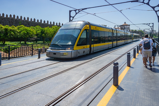 Porto Portugal 13 July 2021 View of a modern yellow tram gliding along the Dom Luís I Bridge contrasting against the ancient stone walls and vibrant green trees. Porto Portugal 13 July 2021 View of a modern yellow tram gliding along the Dom Luís I Bridge contrasting against the ancient stone walls and vibrant green trees.