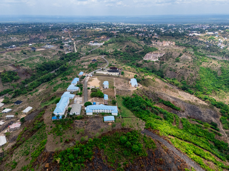 Aerial view of buildings nestled on a hilltop surrounded by verdant vegetation and distant structures under a vast sky Ohafia Abia Nigeria. Aerial view of buildings nestled on a hilltop surrounded by verdant vegetation and distant structures under a vast sky Ohafia Abia Nigeria.