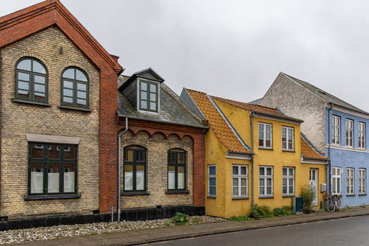 View of colorful historic houses with brick and painted facades along a quiet street in Praesto Seeland Denmark. View of colorful historic houses with brick and painted facades along a quiet street in Praesto Seeland Denmark.