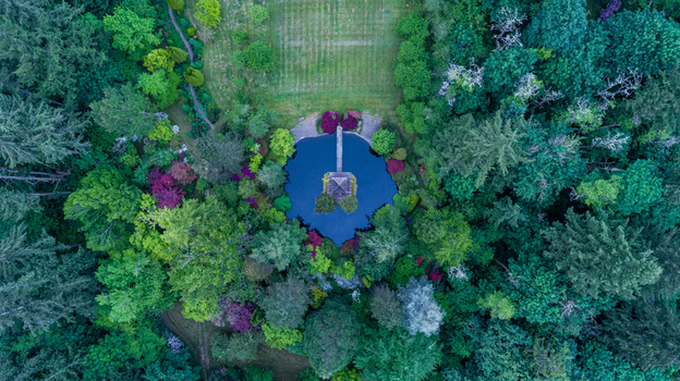 Aerial view of a circular pond with a central gazebo and walkway surrounded by lush forest and colorful foliage near Northwest Skyline Boulevard Portland Oregon United States. Aerial view of a circular pond with a central gazebo and walkway surrounded by lush forest and colorful foliage near Northwest Skyline Boulevard Portland Oregon United States.