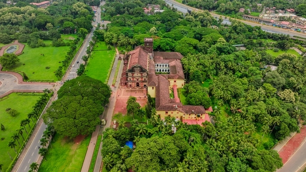 Aerial view of the Church of St. Francis of Assisi surrounded by lush green trees manicured lawns and winding roads in Old Goa Goa India. Aerial view of the Church of St. Francis of Assisi surrounded by lush green trees manicured lawns and winding roads in Old Goa Goa India.