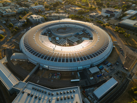 Aerial view of Diamond Light Source a circular synchrotron facility surrounded by greenery under golden hour light in Didcot United Kingdom.