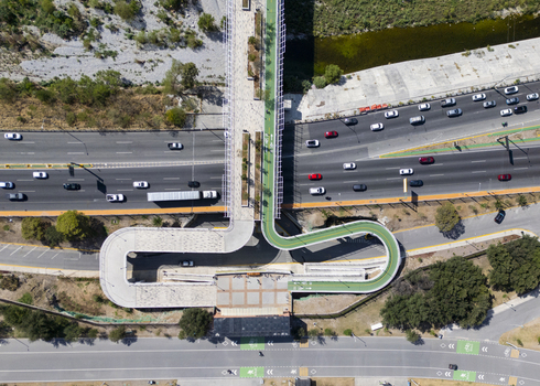 Aerial view of the modern Paseo de la Mujer pedestrian bridge with a green bike lane spanning over a busy highway in Monterrey Nuevo Leon Mexico. Aerial view of the modern Paseo de la Mujer pedestrian bridge with a green bike lane spanning over a busy highway in Monterrey Nuevo Leon Mexico.
