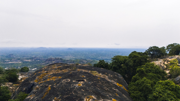 Aerial view of a striking landscape featuring rugged lichen covered rocks contrasted against the lush greenery of trees and distant rolling hills Oyo Oyo Nigeria. Aerial view of a striking landscape featuring rugged lichen covered rocks contrasted against the lush greenery of trees and distant rolling hills Oyo Oyo Nigeria.
