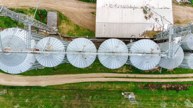 Aerial view of silver silos gleaming under the sun s embrace juxtaposed against the verdant fields and rustic paths a symphony of industry and nature. Sremska Mitrovica Vojvodina Serbia. Aerial view of silver silos gleaming under the sun s embrace juxtaposed against the verdant fields and rustic paths a symphony of industry and nature. Sremska Mitrovica Vojvodina Serbia.