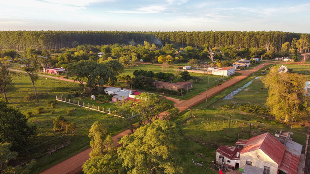 Aerial view of the rural town with dirt roads scattered houses lush green trees and a dense forest backdrop during golden hour in Guaviravi Corrientes Province Argentina. Aerial view of the rural town with dirt roads scattered houses lush green trees and a dense forest backdrop during golden hour in Guaviravi Corrientes Province Argentina.