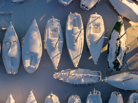 Aerial view of snow covered yachts and boats parked in a winter marina during golden hour in Trakai Vilnius County Lithuania. Aerial view of snow covered yachts and boats parked in a winter marina during golden hour in Trakai Vilnius County Lithuania.