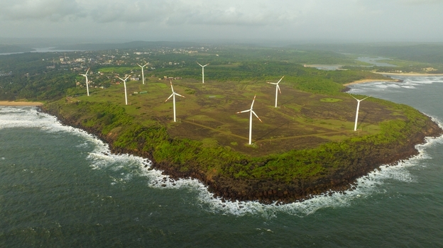 Aerial view of Devgad Windmills on a grassy coastal cliff overlooking the Arabian Sea with lush greenery and waves crashing against the rocky shore in Devgad Maharashtra India. Aerial view of Devgad Windmills on a grassy coastal cliff overlooking the Arabian Sea with lush greenery and waves crashing against the rocky shore in Devgad Maharashtra India.