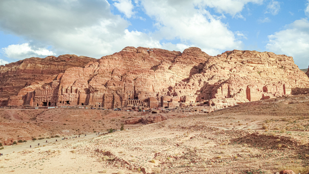 View of the ancient rock cut facades and historic sandstone cliffs of Petra in the desert landscape under a blue sky in Wadi Musa Ma an Governorate Jordan. View of the ancient rock cut facades and historic sandstone cliffs of Petra in the desert landscape under a blue sky in Wadi Musa Ma an Governorate Jordan.