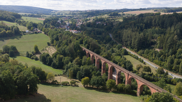 Aerial view of Himbachel Viadukt a historic red sandstone railway bridge surrounded by lush green forests and rolling hills in Erbach Hessen Germany. Aerial view of Himbachel Viadukt a historic red sandstone railway bridge surrounded by lush green forests and rolling hills in Erbach Hessen Germany.