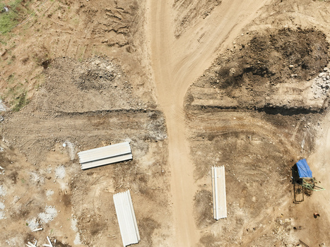 Aerial view of a construction site with dirt paths piles of concrete materials and a small structure covered by a blue tarp in Garut West Java Indonesia. Aerial view of a construction site with dirt paths piles of concrete materials and a small structure covered by a blue tarp in Garut West Java Indonesia.