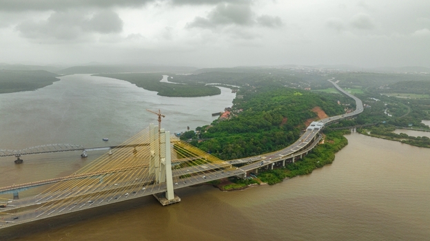 Aerial view of the Zuari Bridge spanning the Zuari River in Goa surrounded by lush greenery and a cloudy sky Cortalim Goa India.