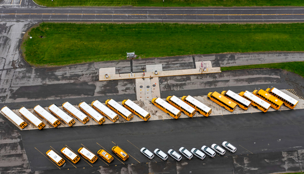 Aerial view of a fleet of yellow school buses parked in neat rows on an asphalt lot in Stockbridge Massachusetts United States. Aerial view of a fleet of yellow school buses parked in neat rows on an asphalt lot in Stockbridge Massachusetts United States.