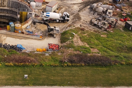 Aerial view of a construction site featuring concrete mixer trucks and an excavator working near a deep circular shaft in Avcilar Istanbul Turkiye. Aerial view of a construction site featuring concrete mixer trucks and an excavator working near a deep circular shaft in Avcilar Istanbul Turkiye.
