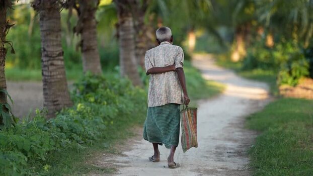 View of an elderly man walking on a rural path in Bangladesh.