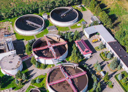 Aerial view of a wastewater treatment plant featuring large circular sedimentation tanks industrial infrastructure and surrounding green trees in Pomeranian Voivodeship Poland. Aerial view of a wastewater treatment plant featuring large circular sedimentation tanks industrial infrastructure and surrounding green trees in Pomeranian Voivodeship Poland.