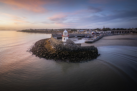 Aerial view of Balbriggan Harbour with its lighthouse stone pier sandy beach and calm sea at sunset in Balbriggan County Dublin Ireland. Aerial view of Balbriggan Harbour with its lighthouse stone pier sandy beach and calm sea at sunset in Balbriggan County Dublin Ireland.