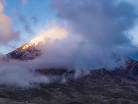 Aerial view of the snow capped peak of Volcano Chimborazo partially obscured by clouds during golden hour in Guano Chimborazo Ecuador. Aerial view of the snow capped peak of Volcano Chimborazo partially obscured by clouds during golden hour in Guano Chimborazo Ecuador.