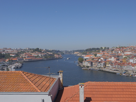 View of the historic city of Porto with its iconic terracotta rooftops lining the Douro River under a clear blue sky in Porto Porto District Portugal. View of the historic city of Porto with its iconic terracotta rooftops lining the Douro River under a clear blue sky in Porto Porto District Portugal.