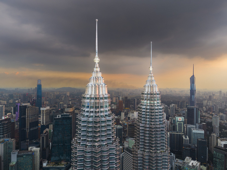Kuala Lumpur Malaysia 11 March 2026 Aerial view of the Petronas Twin Towers rising above the city skyline under a dramatic stormy sky at sunset.