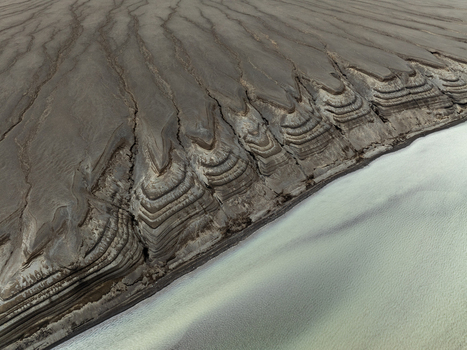 Aerial view of the unique volcanic landscape of Landmannalaugar featuring intricate layered soil formations deep erosion channels and a light colored riverbed in Rangarthing ytra Iceland. Aerial view of the unique volcanic landscape of Landmannalaugar featuring intricate layered soil formations deep erosion channels and a light colored riverbed in Rangarthing ytra Iceland.