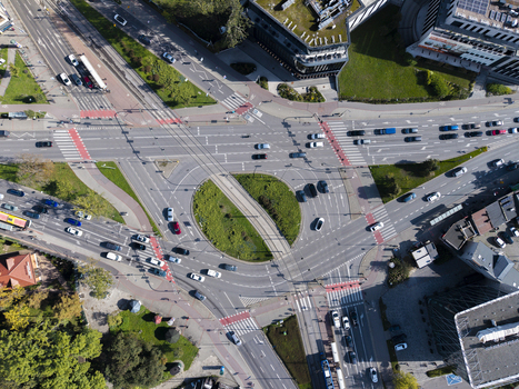 Aerial view of a busy road intersection and roundabout with surrounding urban infrastructure green landscaping and moving traffic in Krakow Lesser Poland Voivode Poland.