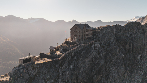 Aerial view of Payer Hutte perched on a rugged rocky ridge of Ortler Mountain surrounded by steep alpine slopes and clear sky in Sulden Trentino Alto Adige Italy. Aerial view of Payer Hutte perched on a rugged rocky ridge of Ortler Mountain surrounded by steep alpine slopes and clear sky in Sulden Trentino Alto Adige Italy.