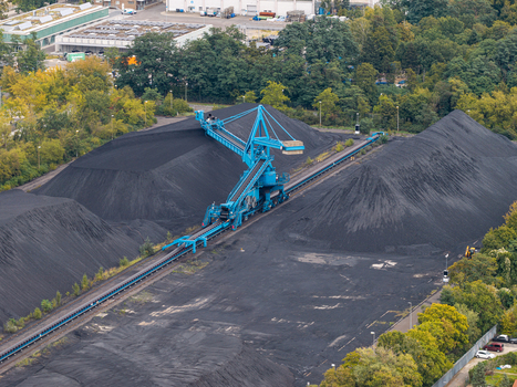 Aerial view of a large blue stacker machine operating on massive piles of coal in an industrial mining area in Berlin Berlin Germany.