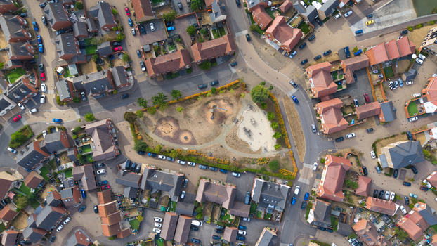 Aerial view of modern residential housing estate featuring a central park with playground equipment surrounded by suburban homes and winding streets in Bedford England United Kingdom. Aerial view of modern residential housing estate featuring a central park with playground equipment surrounded by suburban homes and winding streets in Bedford England United Kingdom.