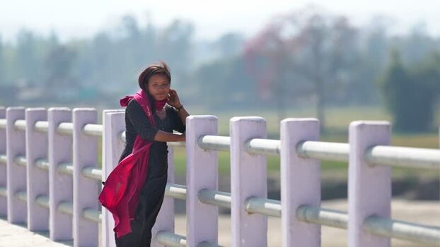 View of a woman leaning on a bridge railing in Dhangadhi Nepal. View of a woman leaning on a bridge railing in Dhangadhi Nepal.