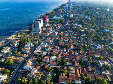 Aerial view of Negombo Beach with its sandy coastline dense urban area featuring red tiled rooftops palm trees and coastal hotels along the Indian Ocean in Negombo Western Province Sri Lanka. Aerial view of Negombo Beach with its sandy coastline dense urban area featuring red tiled rooftops palm trees and coastal hotels along the Indian Ocean in Negombo Western Province Sri Lanka.