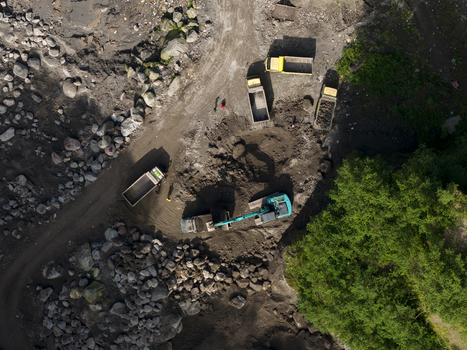 Aerial view of Tambang Pasir Merapi Kali Gendol Sand Mine with an excavator loading sand into trucks near rocks in Kecamatan Cangkringan Daerah Istimewa Yogya Indonesia. Aerial view of Tambang Pasir Merapi Kali Gendol Sand Mine with an excavator loading sand into trucks near rocks in Kecamatan Cangkringan Daerah Istimewa Yogya Indonesia.