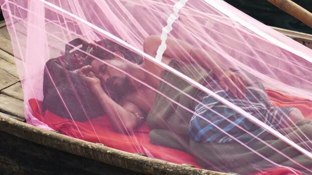 View of a man sleeping under a mosquito net on a boat Bangladesh.