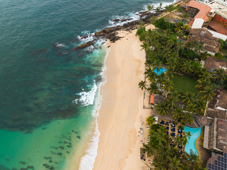 Aerial view of the sandy shoreline and turquoise waters of Unawatuna Beach lined with palm trees and luxury resorts in Unawatuna Southern Province Sri Lanka.