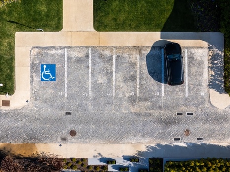 Aerial view of a handicap parking space and a black car parked in a cobblestone parking lot in Cascais Lisboa Portugal. Aerial view of a handicap parking space and a black car parked in a cobblestone parking lot in Cascais Lisboa Portugal.