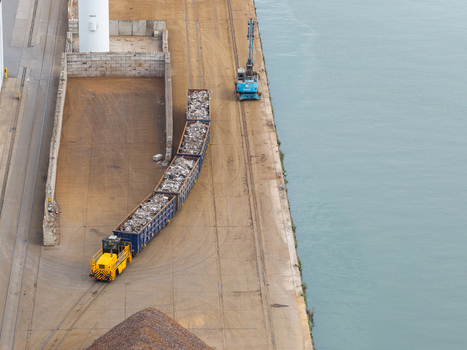Aerial view of a yellow locomotive pulling freight cars filled with scrap metal at Haven Genk Genk Vlaanderen Belgium. Aerial view of a yellow locomotive pulling freight cars filled with scrap metal at Haven Genk Genk Vlaanderen Belgium.