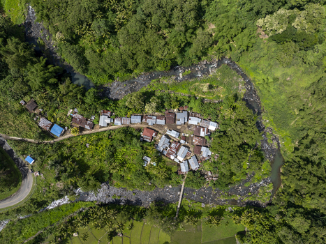 Aerial view of a small village nestled in the lush tropical landscape of Flores with a winding river and dense forest in East Nusa Tenggara Indonesia. Aerial view of a small village nestled in the lush tropical landscape of Flores with a winding river and dense forest in East Nusa Tenggara Indonesia.
