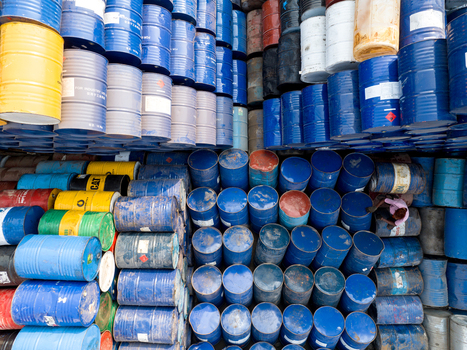 Aerial view of hundreds of colorful industrial oil barrels stacked in a storage yard with a worker standing among them Dhaka Dhaka Division Bangladesh. Aerial view of hundreds of colorful industrial oil barrels stacked in a storage yard with a worker standing among them Dhaka Dhaka Division Bangladesh.