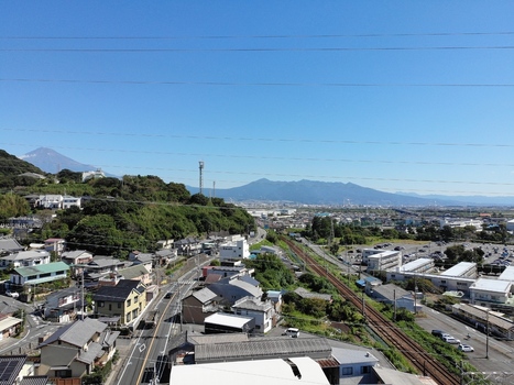 Aerial view of Kanbara in Shimizu Ward with railway tracks residential houses and distant mountains under a clear blue sky in Shizuoka Shizuoka Japan.