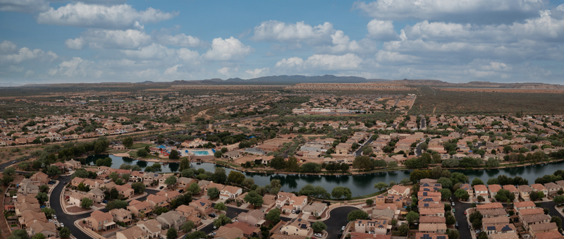Aerial view of homes around Sahuarita Lake in Sahuarita Arizona with suburban neighborhoods desert land and distant mountains.