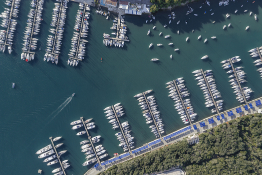 Aerial view of Pjescana Uvala marina featuring rows of yachts and sailboats moored at wooden piers surrounded by lush coastal vegetation in Pula Istarska zupanija Croatia.