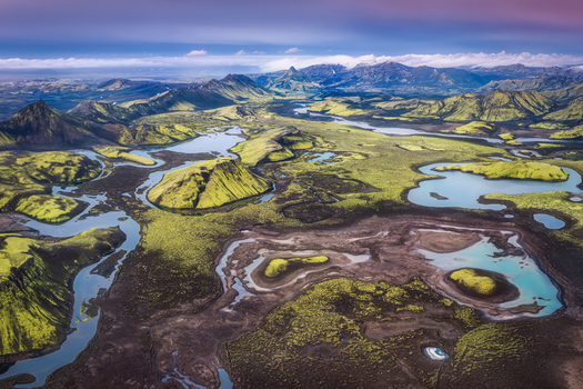 Aerial view of Langisjor lake surrounded by vibrant green moss covered hills winding river channels and volcanic terrain in Skaftarhreppur Iceland.