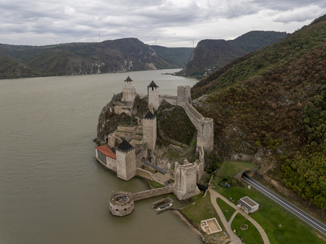 Aerial view of Golubac Fortress on the rocky banks of the Danube river featuring medieval stone towers and walls surrounded by hills under a cloudy sky. Golubac Branicevski okrug Serbia. Aerial view of Golubac Fortress on the rocky banks of the Danube river featuring medieval stone towers and walls surrounded by hills under a cloudy sky. Golubac Branicevski okrug Serbia.