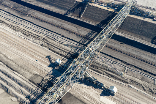 Aerial view of Tagebau Welzow Sud brown coal open pit mine with a massive bucket wheel excavator spanning across the dark earth layers in Spremberg Brandenburg Germany. Aerial view of Tagebau Welzow Sud brown coal open pit mine with a massive bucket wheel excavator spanning across the dark earth layers in Spremberg Brandenburg Germany.