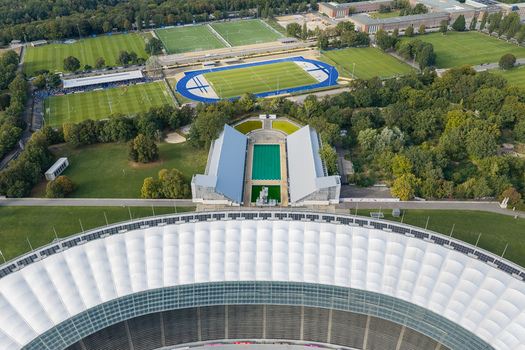 Berlin Germany 26 September 2026 Aerial view of Olympiastadion Berlin with its iconic white roof surrounding sports fields and lush greenery under a clear sky.