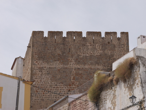 View of the historic stone tower of the Portalegre castle with its crenellated battlements rising above traditional white walled buildings in Portalegre Portalegre District Portugal.
